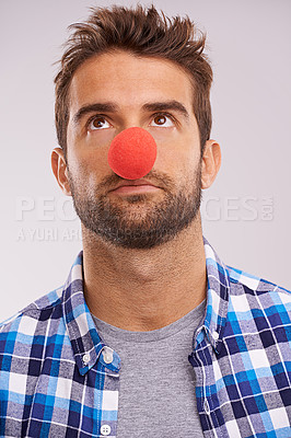 Buy stock photo Clown, nose and man thinking with funny, crazy and comedy with idea in a studio. Costume, quirky and looking up with a male person with grey background and comedian ready for a joke with red prop