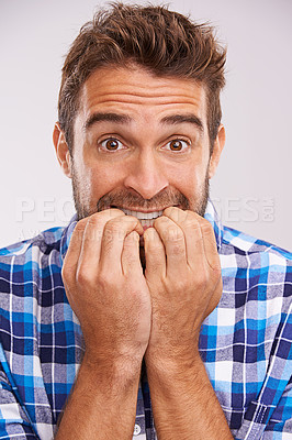 Buy stock photo Nervous, portrait and man with nail bite for anxiety, fear and funny stress gesture in a studio. Worried, scared and male person with hands to face for comedy with grey background and modern style