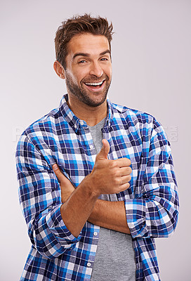 Buy stock photo Portrait, excited and man with thumbs up for winning, success or feedback for support isolated on a gray studio background. Face, happy person and like hand gesture for emoji, agreement or laughing