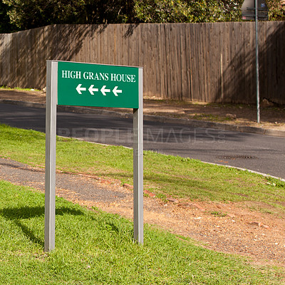 Buy stock photo Road sign, arrow and outdoor for direction in neighborhood to search for houses, address and funny joke. Green board, signage and pointing on grass, lawn and comic text with mistake, error or humor