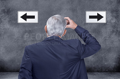 Buy stock photo A rear view of thinking, confused and deciding businessman struggling and trying to decide which way to go. Indecisive corporate worker chooses direction with left and right arrow sign on black wall