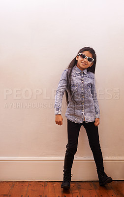 Buy stock photo Girl, child and fashion or sunglasses for style and looking cool on a wall background at home. Happy portrait of a kid or child with trendy clothes, casual and accessory or shades for fun indoors