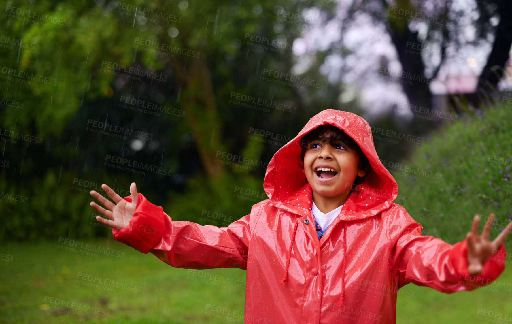 Buy stock photo Rain, celebration and excited boy in a forest for adventure, freedom or exploring games in nature. Winter, travel and happy kid with raincoat in India outdoor for learning, journey or storm surprise