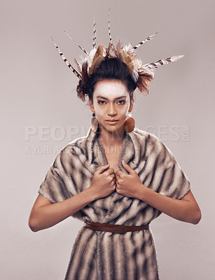 Buy stock photo Woman, portrait and Native American with fashion for culture, tradition or art on a gray studio background. Female person with feather, face paint or stylish tribal clothing of goddess in beauty