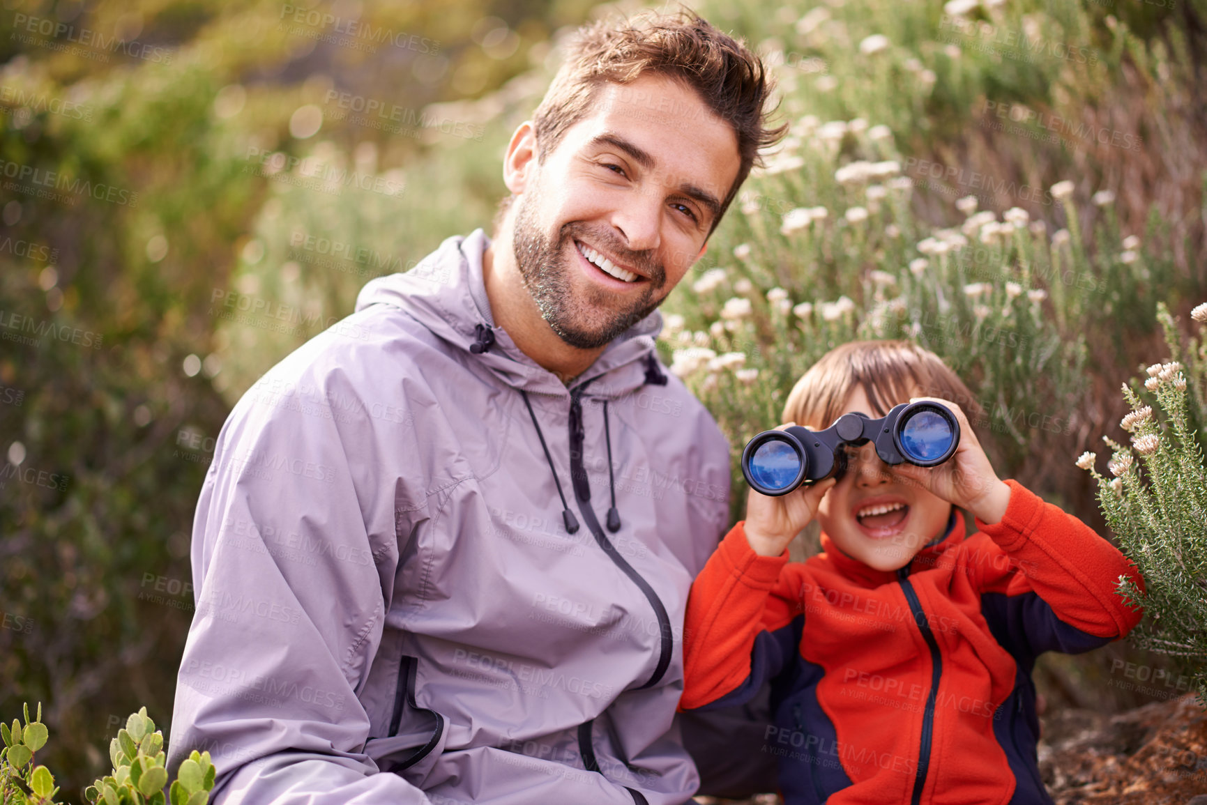 Buy stock photo Shot of a little boy looking through binoculars while on a hike with his father