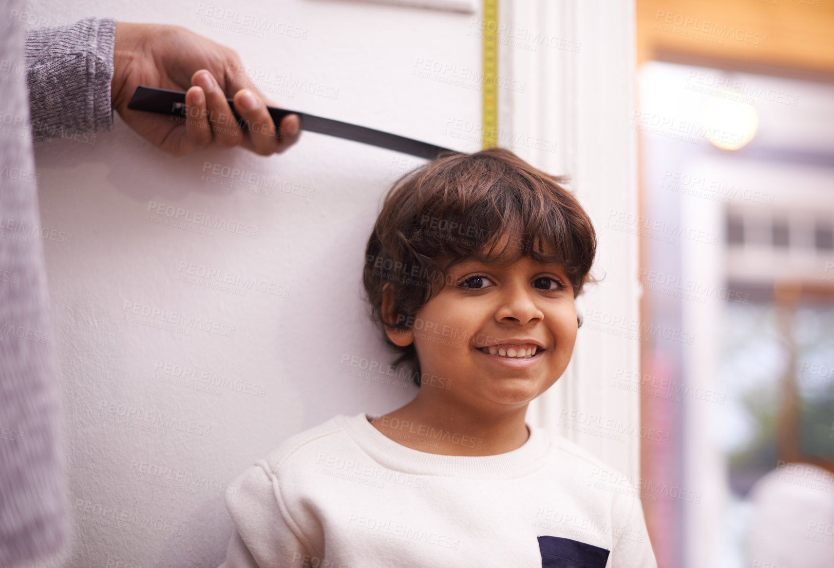 Buy stock photo Child, portrait and measure height growth with ruler for childhood development, taller or elementary school. Boy, student and face with hand or tape at wall in apartment for checking, size or happy