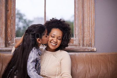 Buy stock photo Kiss, mother and girl with a smile, home and loving with joy, relationship and happiness. Family, parents and mama with kid, female child and kissing in the living room, care and bonding on a couch