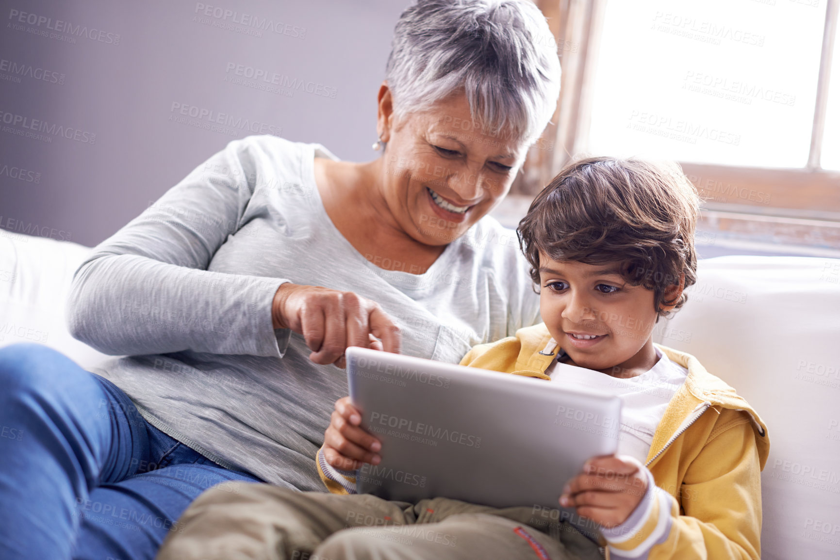 Buy stock photo Tablet, grandmother and kid education app at home on living room sofa with happiness and bonding. Family, house couch and lounge with senior woman and child on technology watching a video with smile