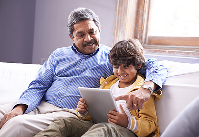 Buy stock photo Shot of a grandfather and grandson sitting on a sofa using a digital tablet