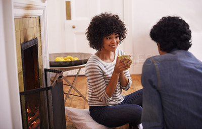 Buy stock photo Coffee, conversation and young couple in living room by fireplace bonding together in winter. Happy, love and man and woman drinking cappuccino, latte or espresso in lounge at modern apartment. 