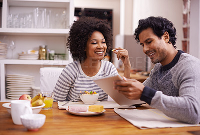 Buy stock photo Shot of a happy couple enjoying breakfast together while looking a digital tablet