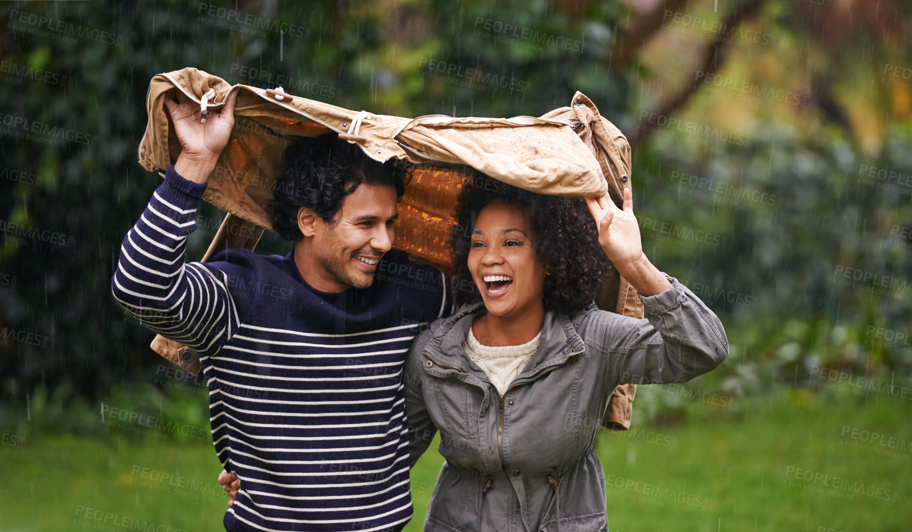 Buy stock photo Cropped shot of an affectionate young couple trying to escape the rain