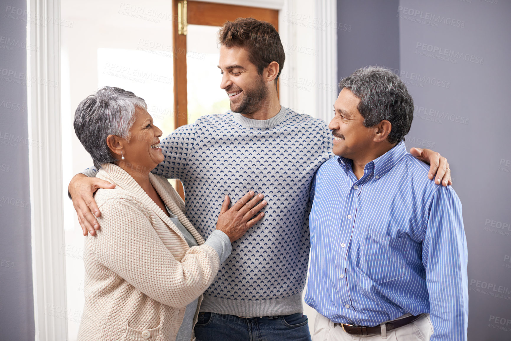 Buy stock photo Shot of a senior couple embracing standing with their adult son