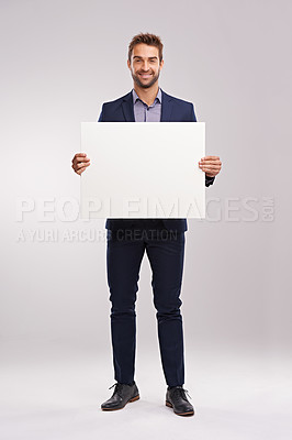 Buy stock photo Studio shot of a handsome man in a suit holding up a blank sign