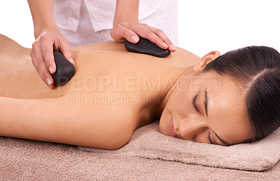 Buy stock photo Hands, hot stone and woman with back massage at spa for wellness, self care and grooming treatment in studio. Skin, calm and female person with masseuse for warm rock body routine by white background