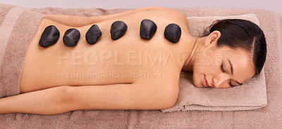 Buy stock photo Calm, hot stone and woman with back massage at spa for wellness, self care and grooming treatment for healing. Skin, girl and high angle of person with warm rock body routine on table for zen.