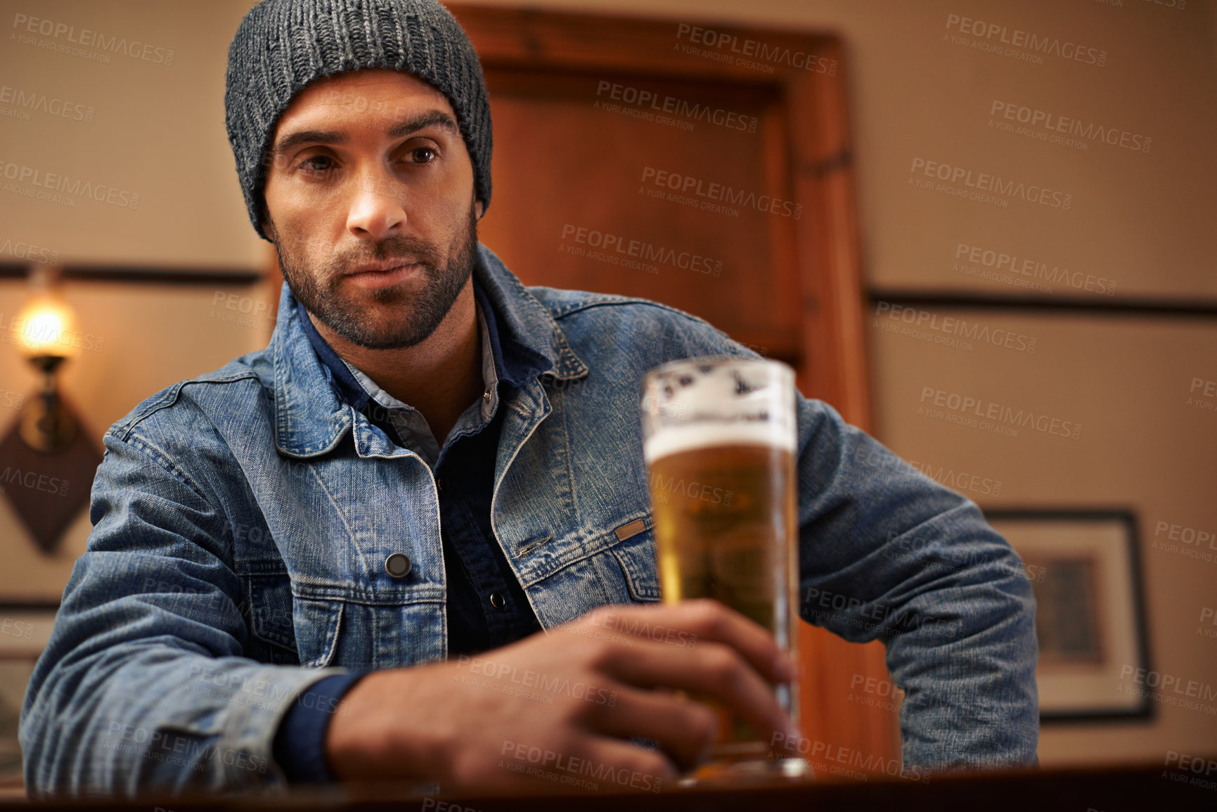 Buy stock photo Beer, pub and male person thinking with alcohol, drinks and restaurant for entertainment. Pensive, lonely and bar for thoughtful or social for relax, night and beanie for cold weather in England  