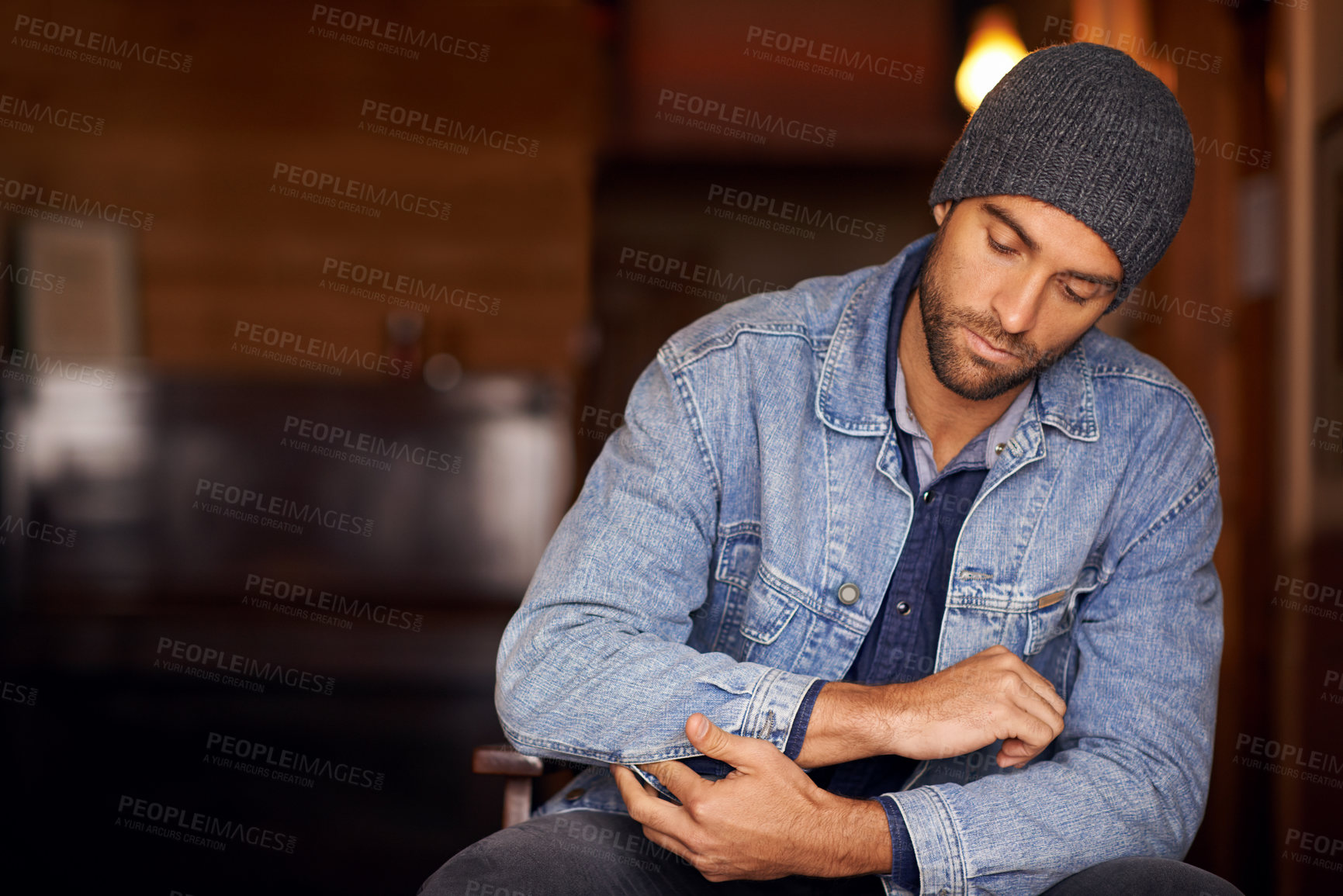 Buy stock photo Man, trendy and winter fashion in home, house and hipster with serious male person sitting in warm clothes. Beanie, head wear for comfort, indoor and fixing denim jacket for urban trends in Canada