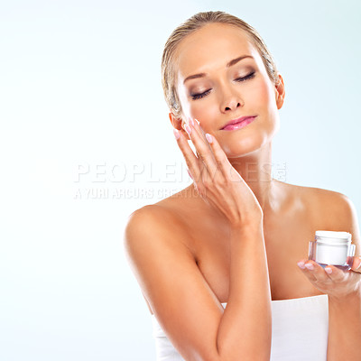 Buy stock photo Mockup, woman and portrait with skincare cream for self care, cosmetics and application in studio. Female person, satisfaction and facial product with beauty, lotion and glow on blue background