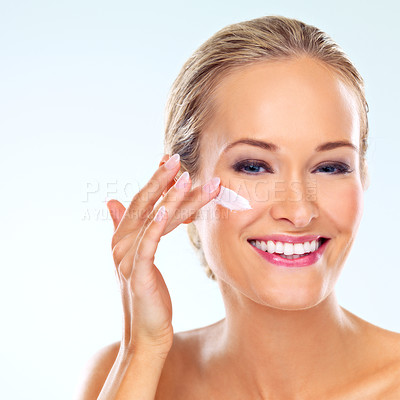 Buy stock photo Happy, woman and portrait with cream on face for skincare, cosmetics, and self care in studio. Female person, smile and facial product with lotion, dermatology or beauty shine on blue background