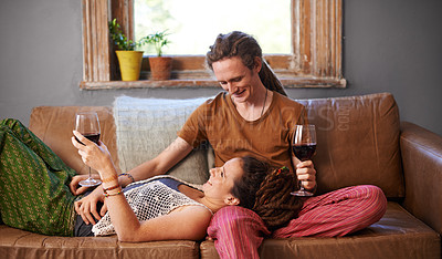 Buy stock photo Shot of a young dreadlocked couple drinking wine on their sofa