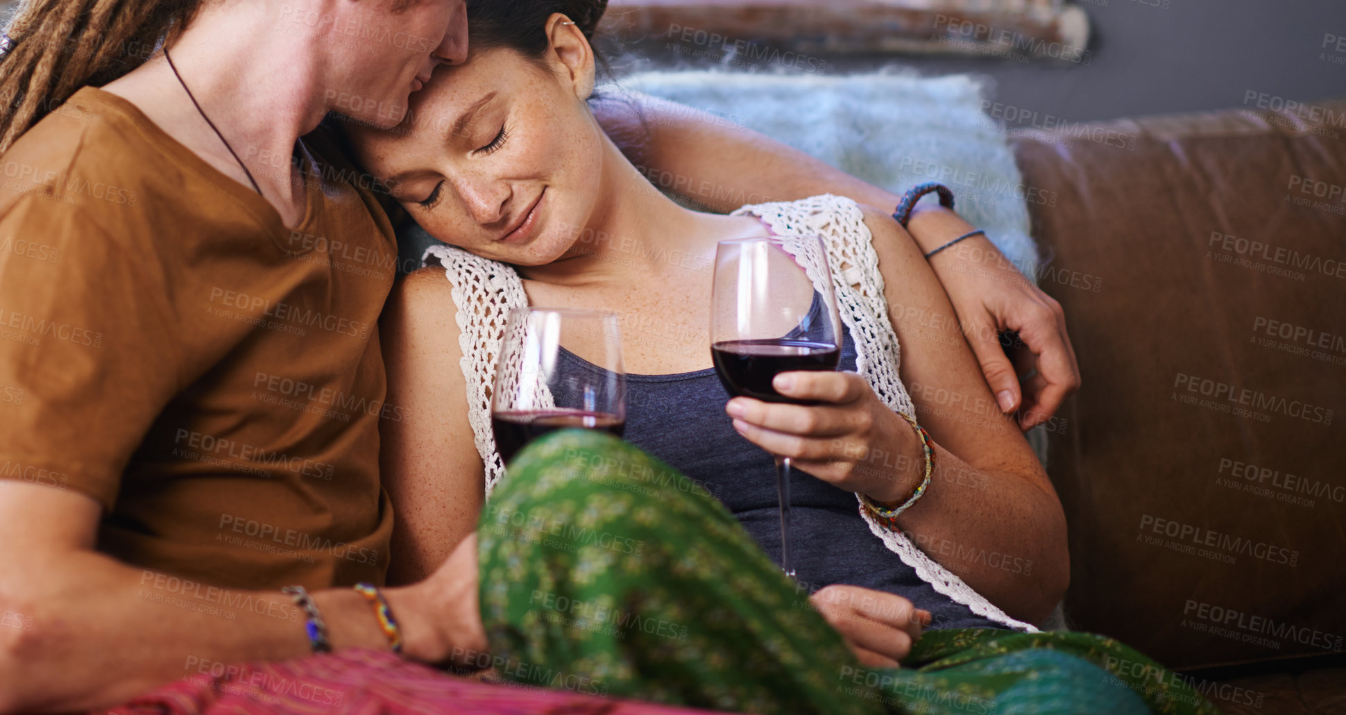 Buy stock photo Shot of a young dreadlocked couple drinking wine on their sofa