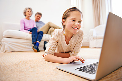 Buy stock photo Shot of grandparents watching their granddaughter using a laptop