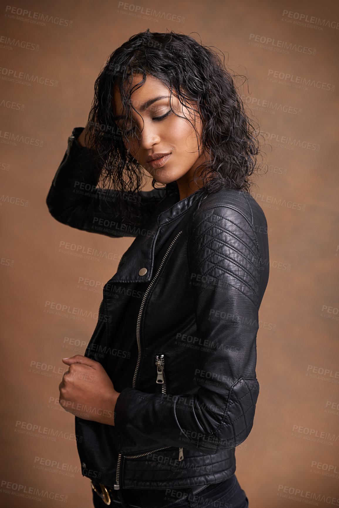 Buy stock photo Thinking, beauty and woman with fashion, leather jacket and confident girl on a brown studio background. Stylish clothes, model and Indian person with casual outfit and happy with edgy and trendy