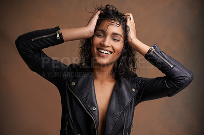 Buy stock photo Studio shot of an attractive young woman in a leather jacket against a brown background