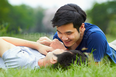 Buy stock photo Asian men, gay couple and lying in park, grass or garden with love, care and bonding with kiss in summer. Happy Japanese guy, romantic and relax together on lawn for lgbtq, smile, outdoor in nature