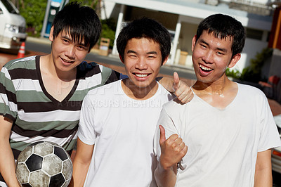 Buy stock photo Asian men, friends and portrait with soccer ball, thumbs up and smile at campus together for sport outdoor. Happy Japanese students, group and yes icon with football for training, exercise or games