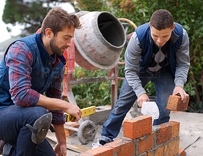 Buy stock photo Men, tools and bricks in outdoor with cement for construction, building or masonry for job or skill. Young people, bricklayer or artisan and talking with equipment for builder or worker for wall