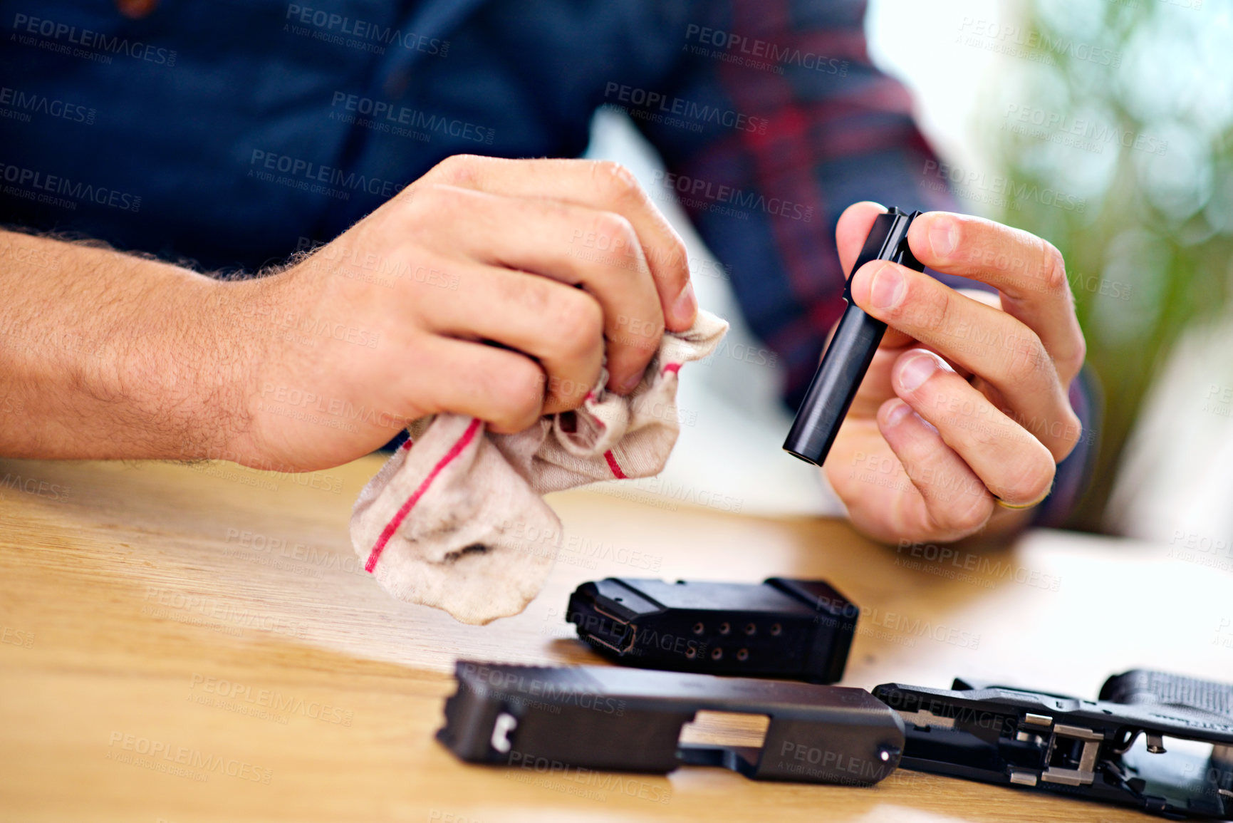 Buy stock photo Hands, cleaning and man with gun at table for safety, self defense and handgun assembly. Process, equipment and person with firearm maintenance with cloth, magazine and wiping dust, dirt and oil