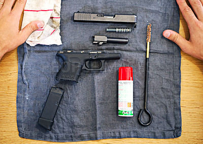 Buy stock photo Hands, cleaning and man with gun on cloth for safety, self defense and handgun assembly. Process, equipment and person with firearm maintenance, magazine and metal parts to assemble weapon on table