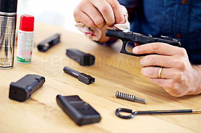 Buy stock photo Hands, man with gun cleaning process at table for safety, self defense and handgun assembly. Caution, equipment and person with firearm maintenance with cloth, magazine and wiping dust, dirt and oil