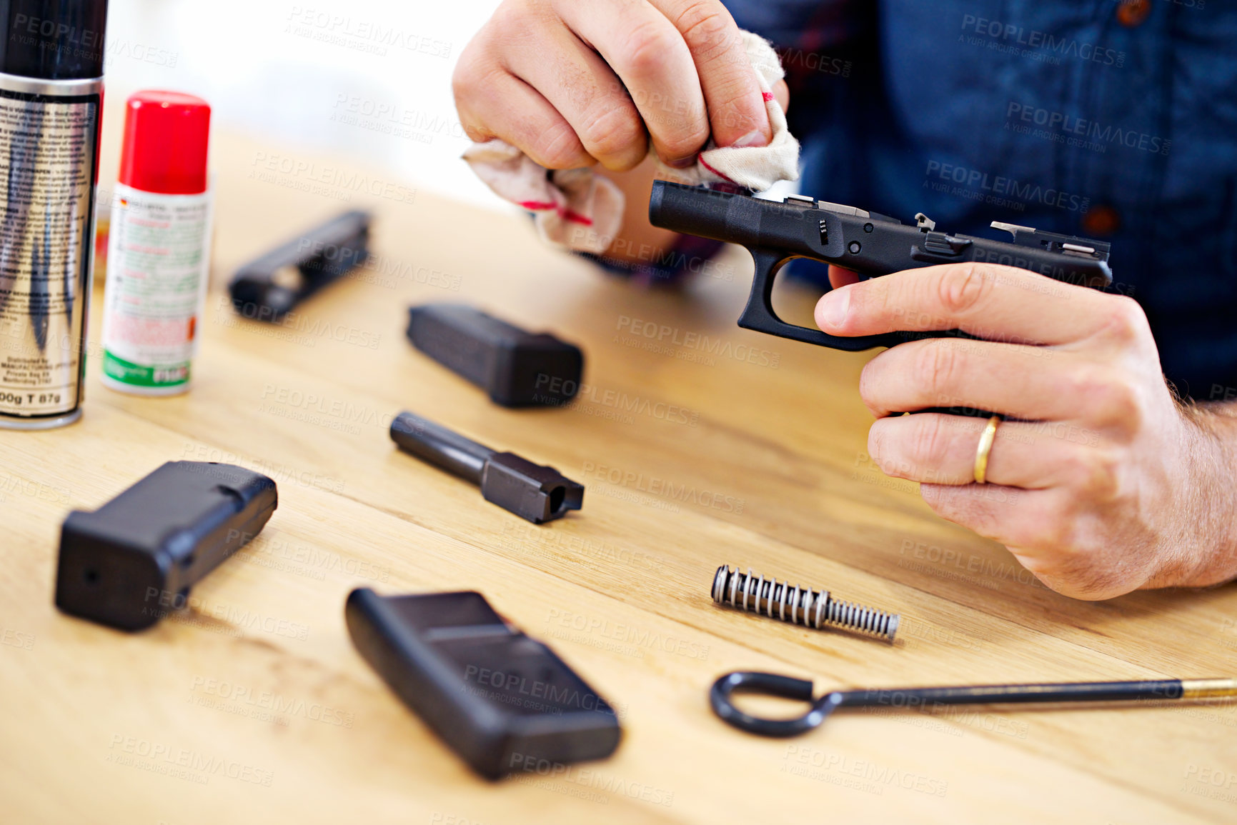 Buy stock photo Hands, man with gun cleaning process at table for safety, self defense and handgun assembly. Caution, equipment and person with firearm maintenance with cloth, magazine and wiping dust, dirt and oil