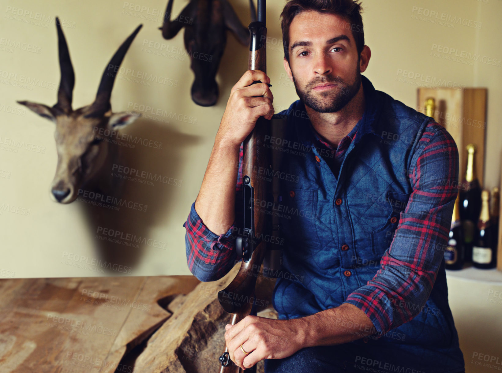 Buy stock photo Hunter, trophy and portrait of man with gun for game shooting, adventure and hobby with confidence. Sports hunting and serious person in cabin with rifle, pride and animal head collection in home