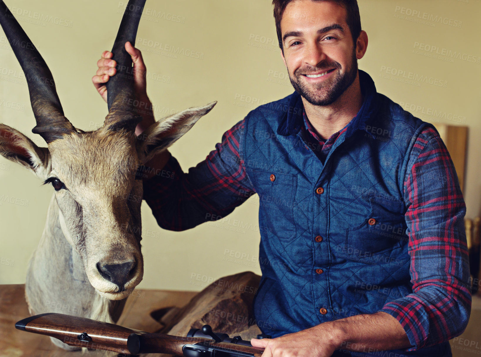 Buy stock photo Hunter, trophy and portrait of happy man with gun for game shooting, adventure and hobby with confidence. Sports hunting and person in cabin with rifle, pride and animal head collection with smile