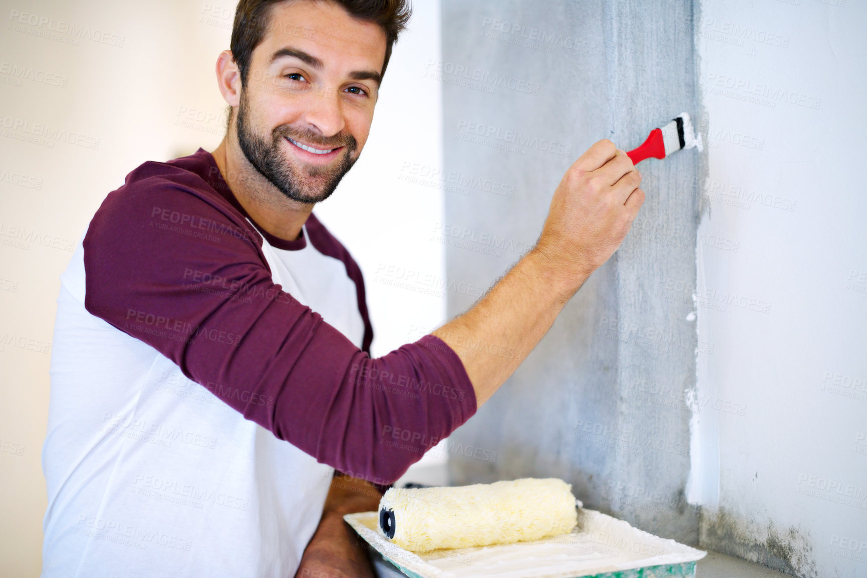 Buy stock photo Shot of a young man painting a wall indoors