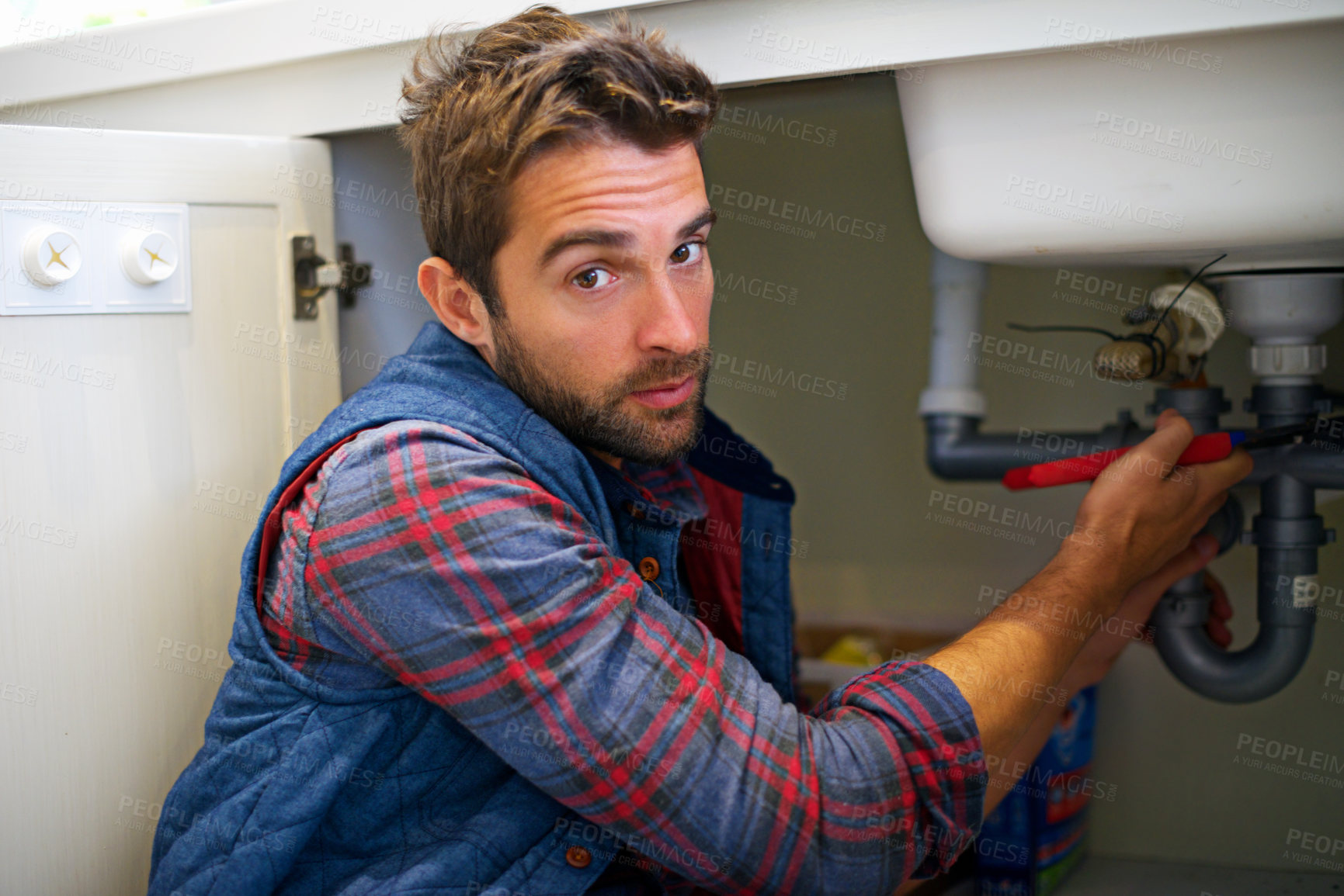 Buy stock photo Man, portrait and plumbing with wrench for pipe repair, service or fix in home maintenance or indoor leak. Male person, plumber or handyman smile with water damage or sink with professional at house