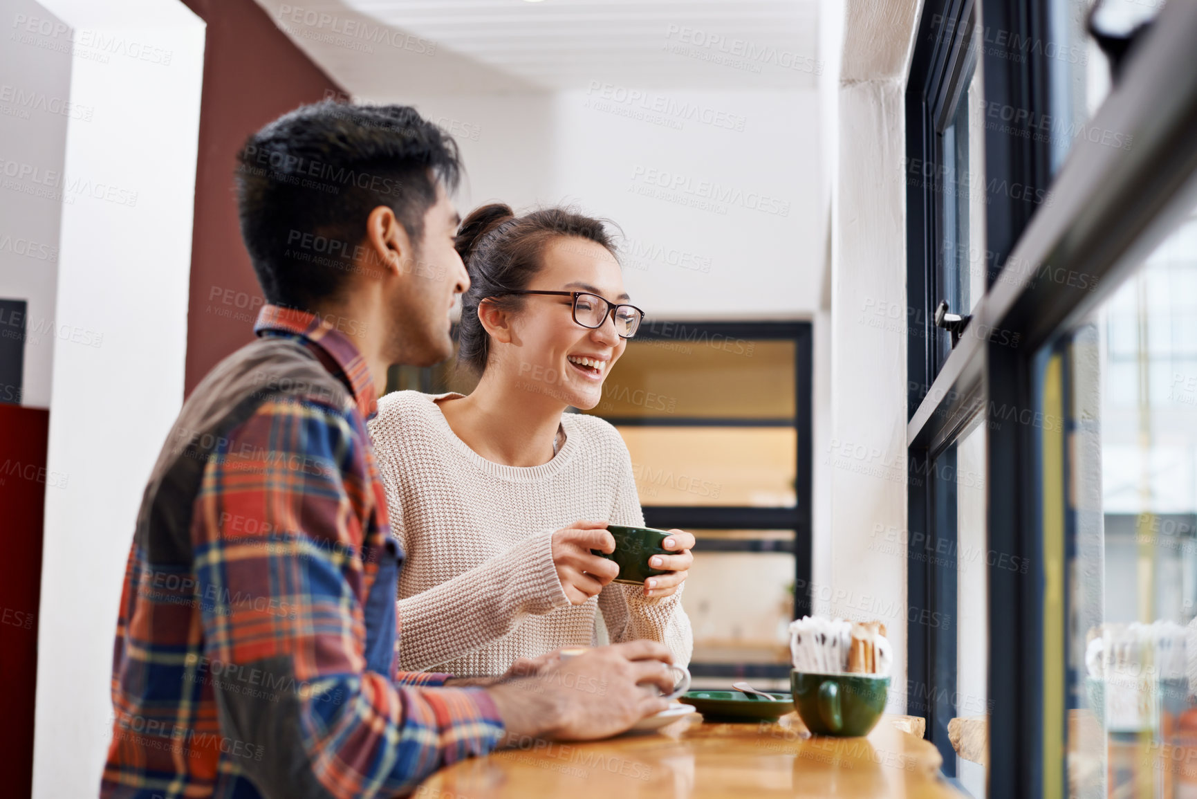 Buy stock photo Happy couple, laughing and window with coffee for morning, breakfast or chatting together at indoor restaurant. Young man and woman with smile in happiness for social bonding or talking at cafe table