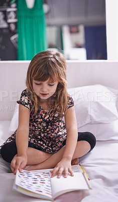 Buy stock photo Shot of a little girl reading a book on her bed