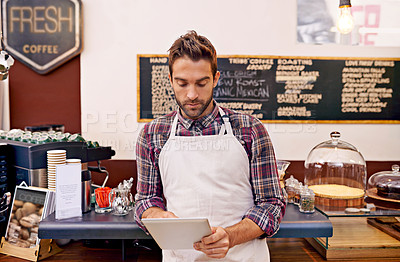 Buy stock photo Shot of a young barista using a digital tablet in a cafe