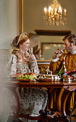 Buy stock photo Queen, king and couple with wine, happy and relax together at dinner, celebration or party in royal mansion. Woman, man and smile with glass, alcohol or drink with food for event in Victorian palace