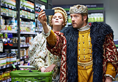 Buy stock photo A king and queen taking a selfie in their local supermarket