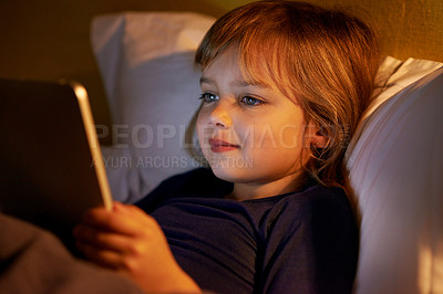 Buy stock photo A little girl lying in bed with a digital tablet