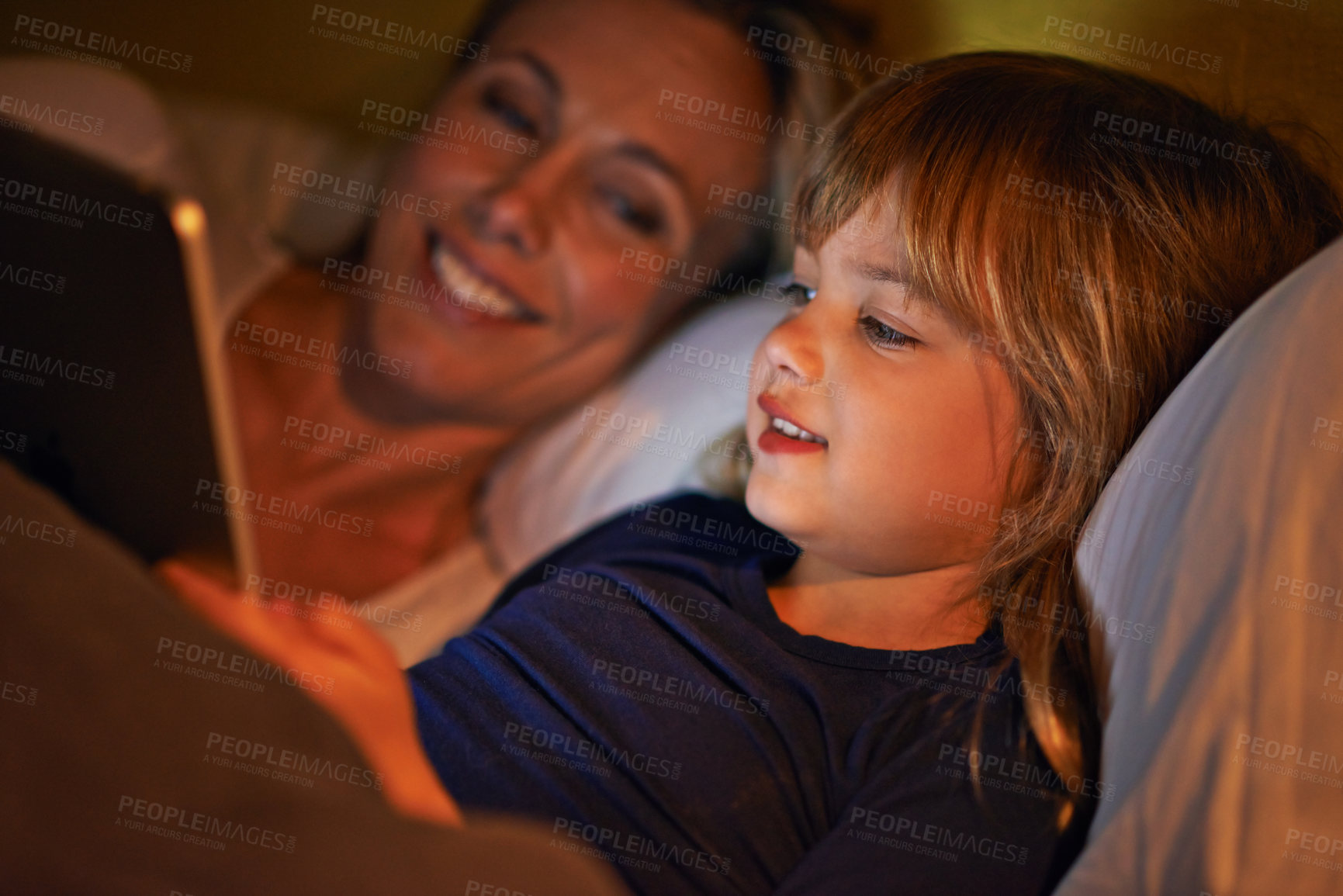 Buy stock photo A mother and daughter lying in bed with a digital tablet