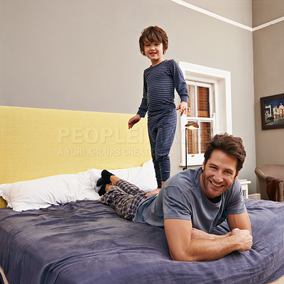 Buy stock photo Happy, jumping and father with kid on bed bonding, playing and having fun together at modern home. Laughing, smile and boy child standing on dad laying in bedroom on weekend at family house in Canada