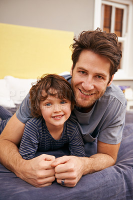 Buy stock photo Smile, portrait and father with child on bed bonding, relaxing and resting together at modern home. Happy, excited and young dad laying with boy kid in bedroom on weekend at family house in Canada.