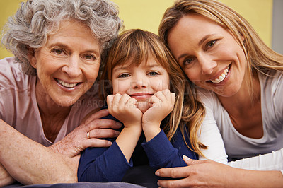 Buy stock photo Portrait of a little girl and her mother and grandmother lying on a bed